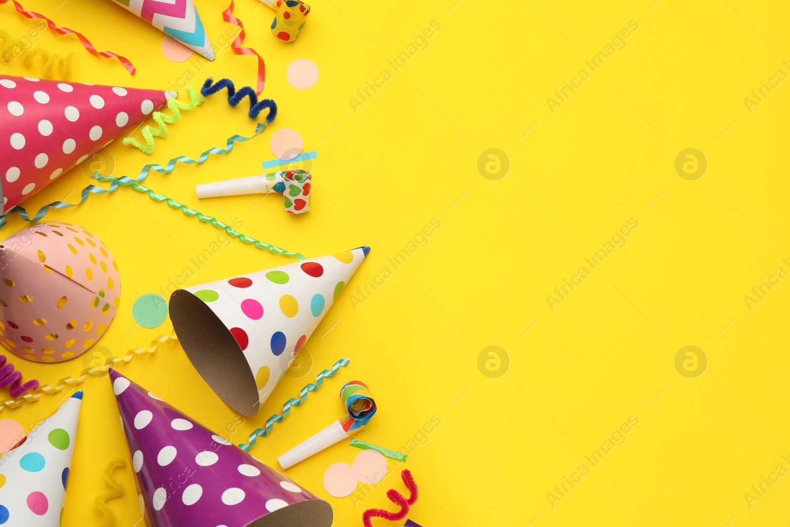 Photo of Flat lay composition with party hats and other festive items on yellow background. Space for text