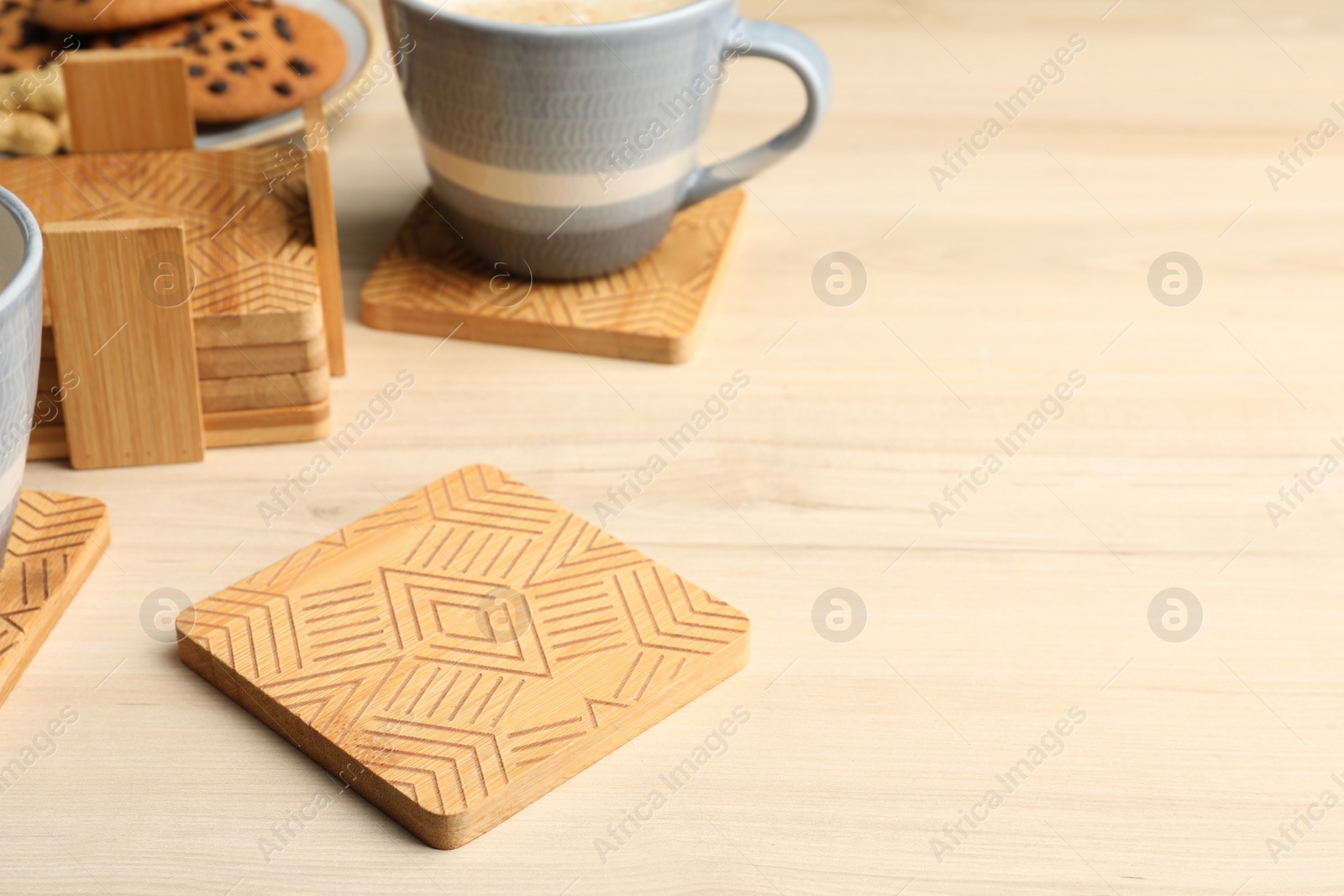 Photo of Many stylish wooden cup coasters and mug on table