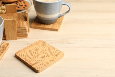 Many stylish wooden cup coasters and mug on table