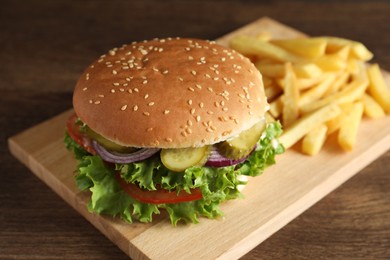Delicious burger with beef patty and french fries on wooden table, closeup