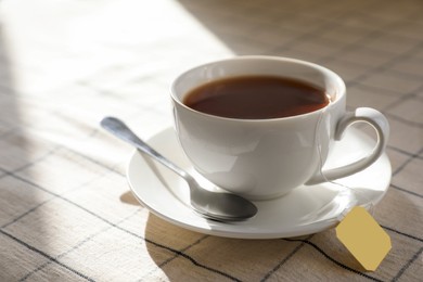 Photo of Bag of black tea in cup on table, closeup. Space for text