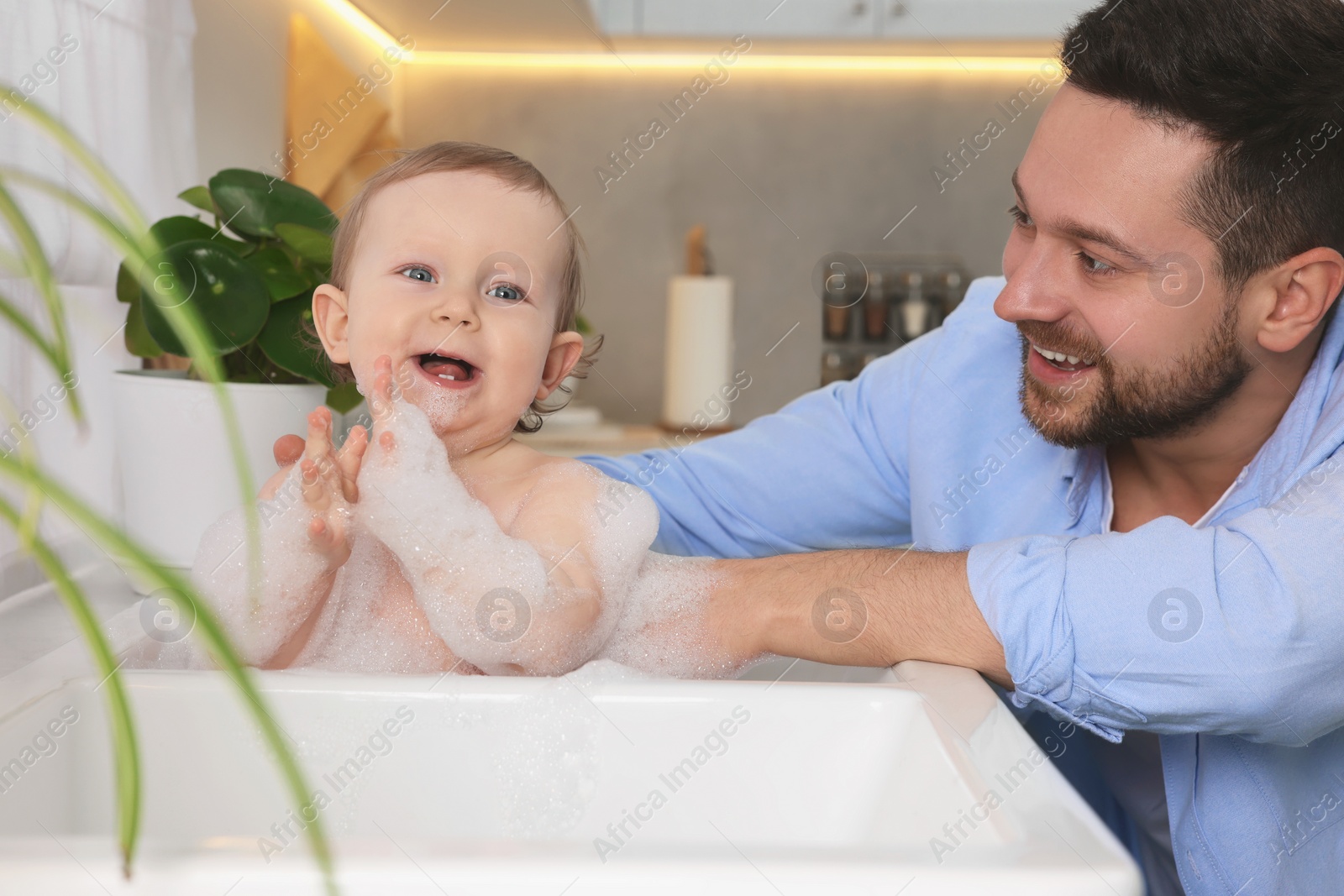 Photo of Father washing his little baby in sink at home