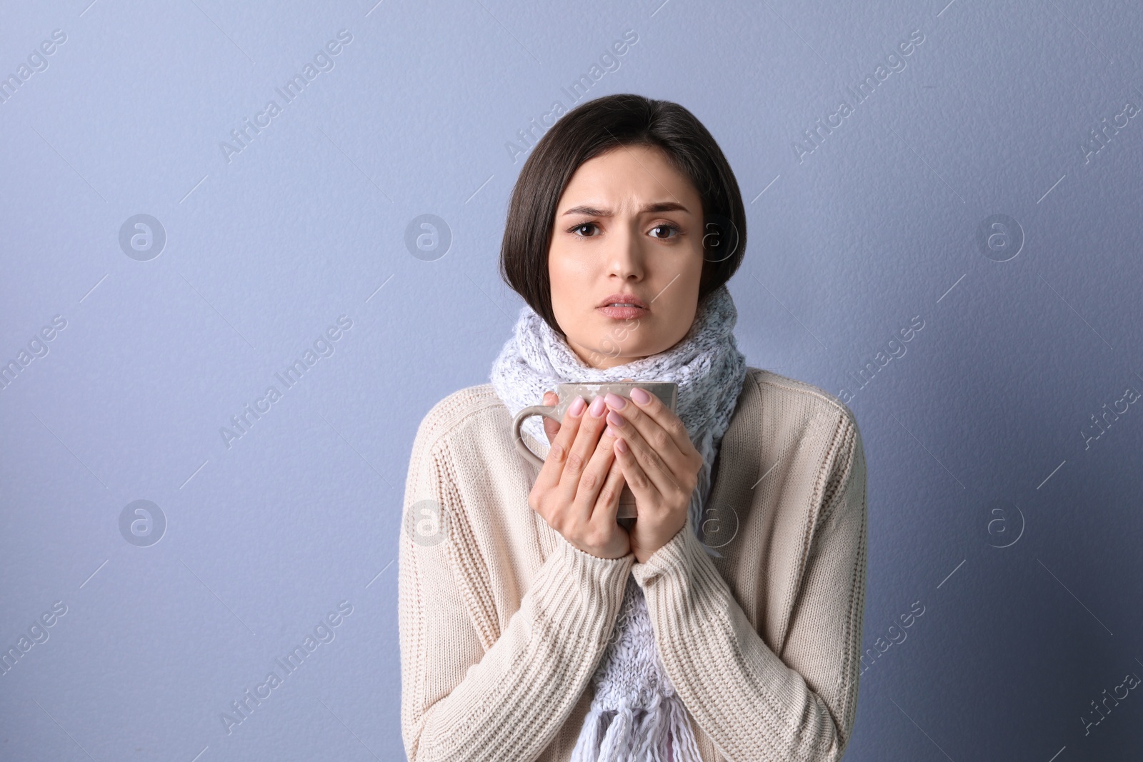 Photo of Young woman with cup of hot tea suffering from cold on color background