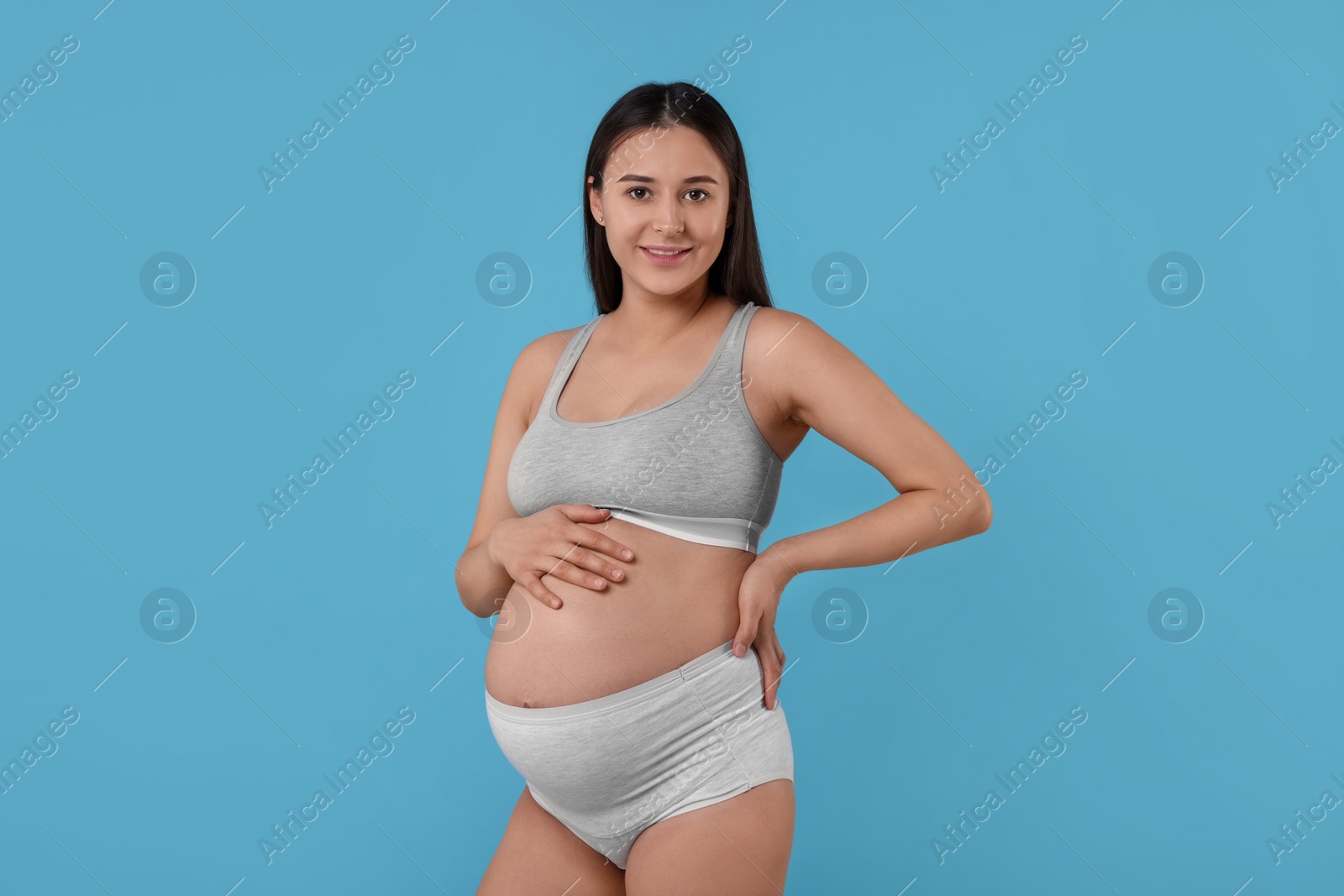 Photo of Beautiful pregnant woman in comfortable maternity underwear on light blue background