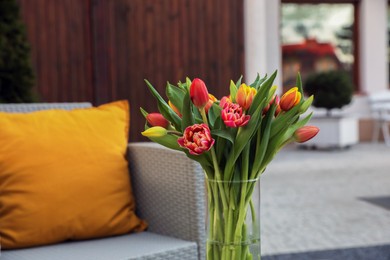 Photo of Beautiful bouquet of colorful tulips in glass vase outdoors