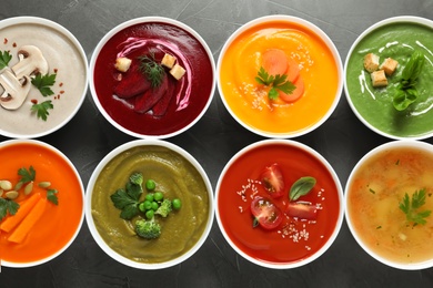 Various cream soups in bowls on grey background, top view