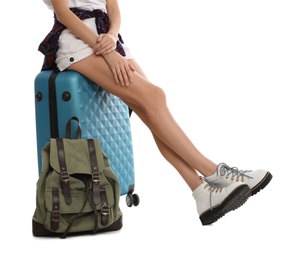 Photo of Woman sitting on suitcase near backpack against white background, closeup. Summer travel