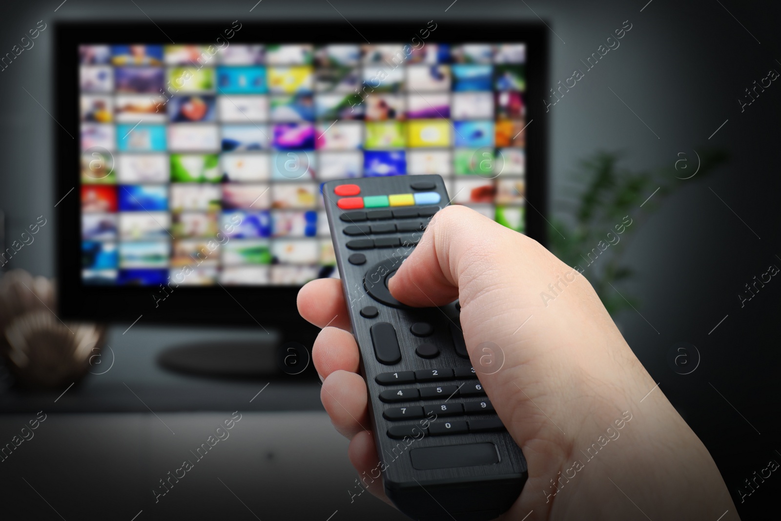 Image of Streaming video services. Woman using remote control to change channels on TV, closeup