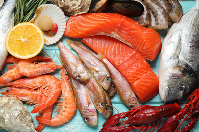 Photo of Fresh fish and different seafood on blue wooden table, flat lay