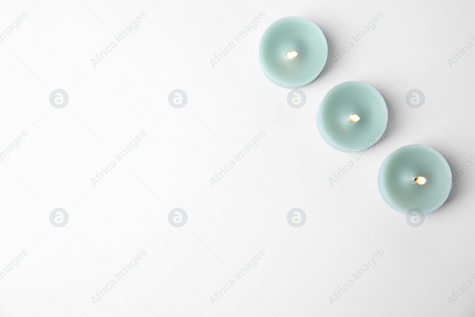 Photo of Light blue wax decorative candles isolated on white, top view