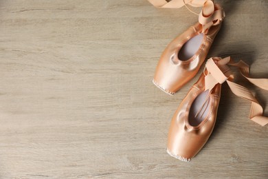 Photo of Ballet shoes. Elegant pointes on wooden floor, flat lay with space for text