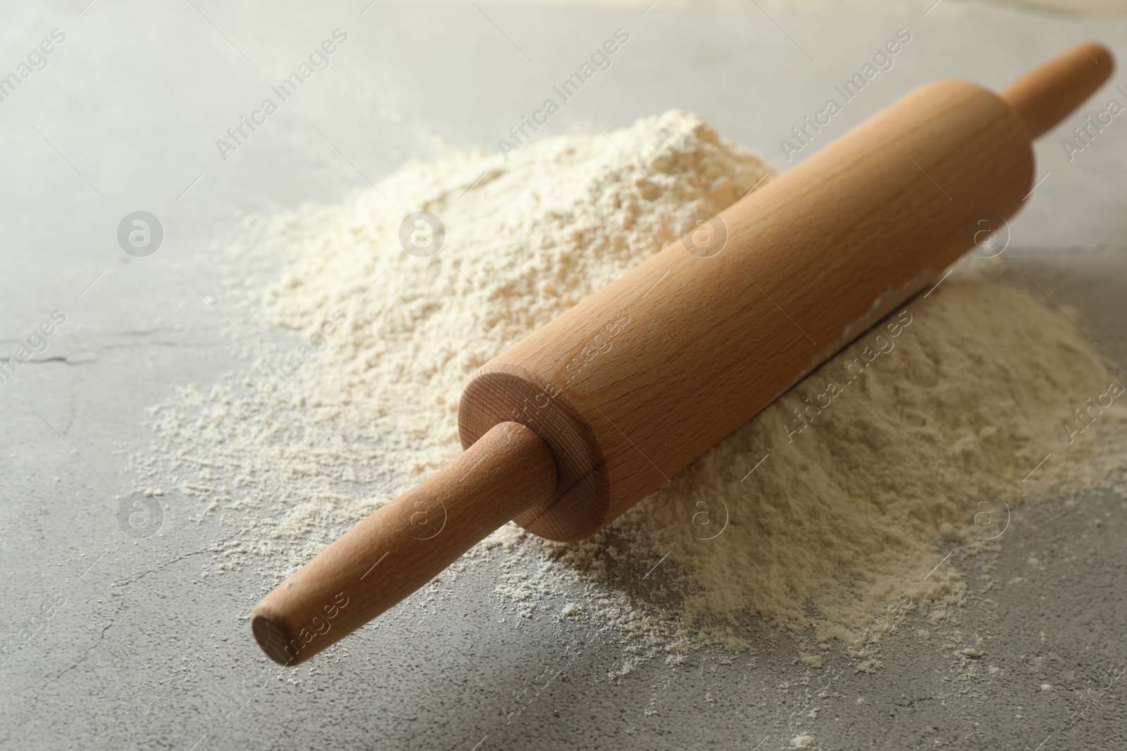 Photo of Flour and rolling pin on grey table, closeup