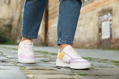 Photo of Woman in stylish sneakers walking on city street, closeup