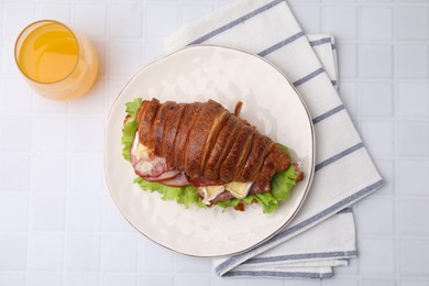 Photo of Tasty croissant with brie cheese, ham and bacon on white tiled table, flat lay