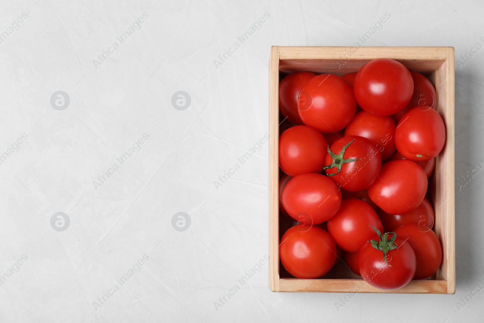 Photo of Wooden crate filled with fresh delicious tomatoes on table, top view. Space for text