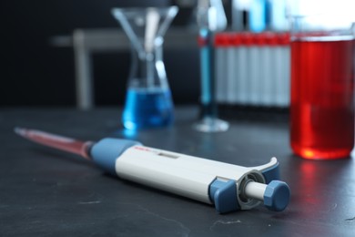 Photo of Laboratory analysis. Micropipette with liquid on black table, closeup