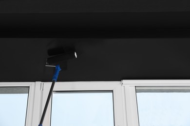 Painting ceiling with black dye indoors, low angle view. Space for text