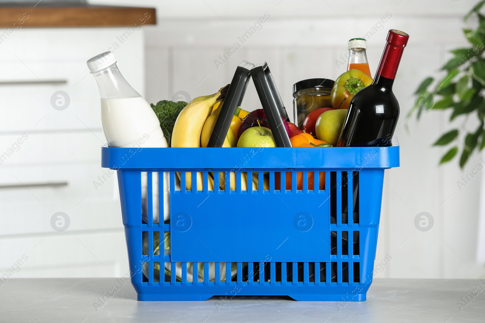 Photo of Shopping basket with grocery products on grey table indoors