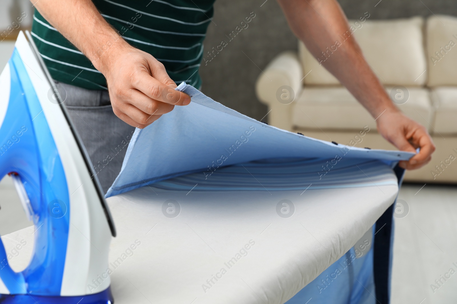 Photo of Man ironing shirt on board at home, closeup