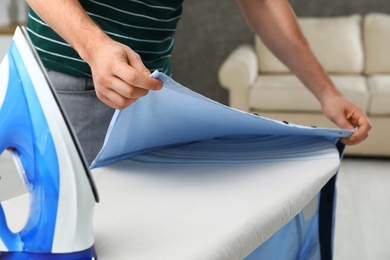 Man ironing shirt on board at home, closeup