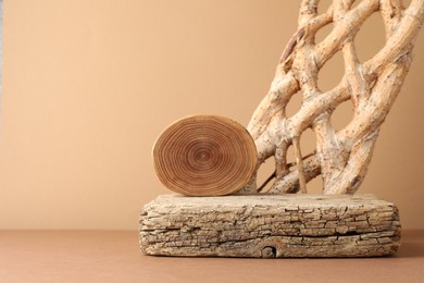 Photo of Presentation for product. Wooden podium and braided tree trunk on beige background. Space for text