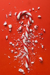 Crushed candy cane on red background, flat lay. Traditional Christmas treat