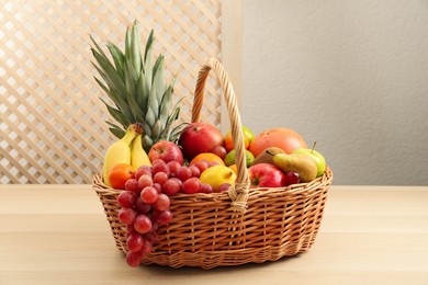 Wicker basket with different fresh fruits on wooden table