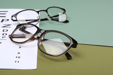 Photo of Vision test chart and glasses on color background, closeup