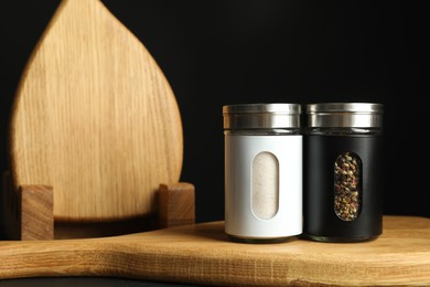 Photo of Salt and pepper shakers on table against black background