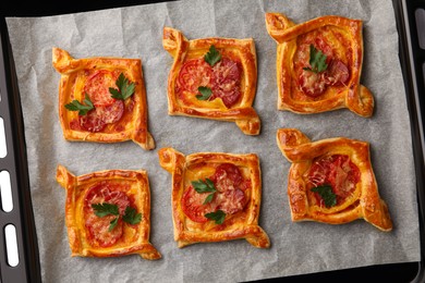 Fresh delicious puff pastry with tasty filling on baking sheet, top view