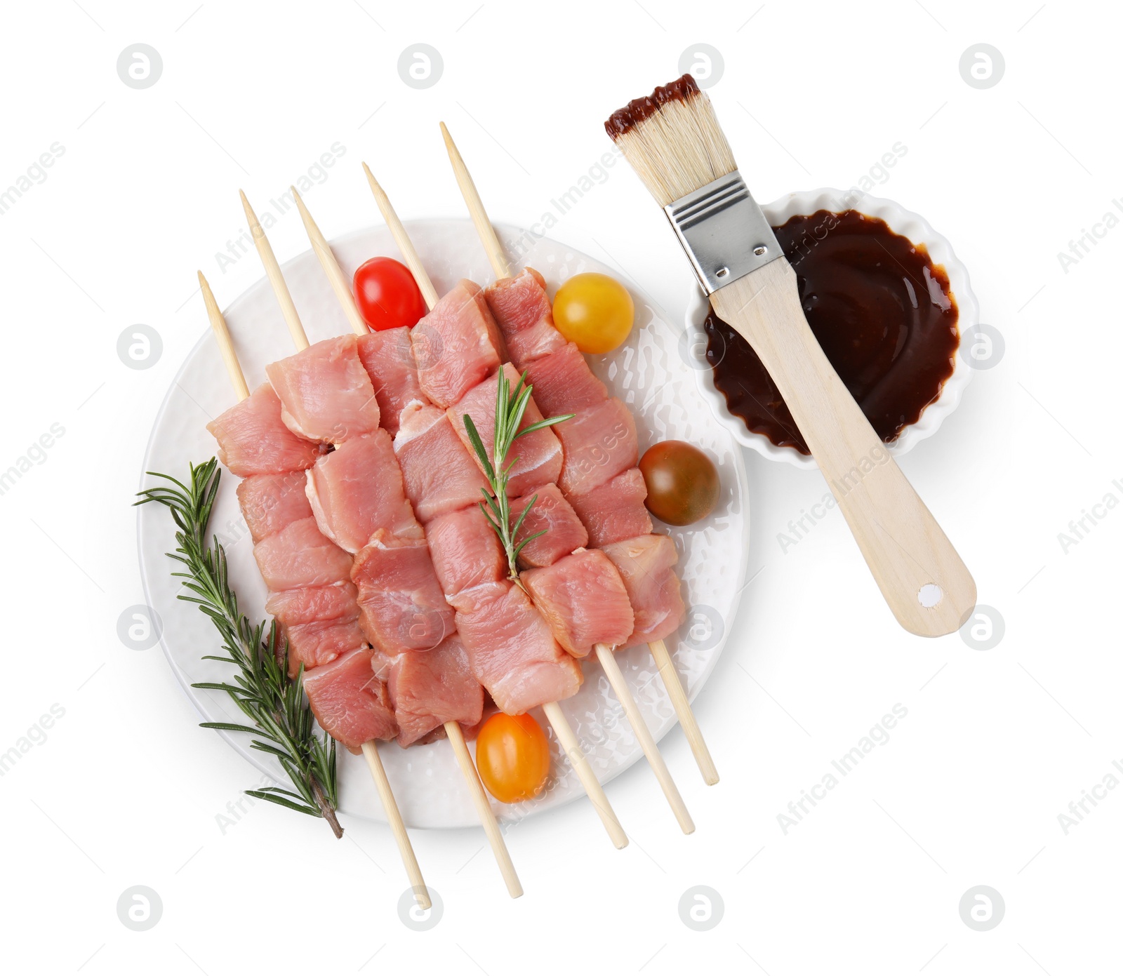 Photo of Skewers with pieces of raw meat, rosemary, tomatoes and marinade isolated on white, top view