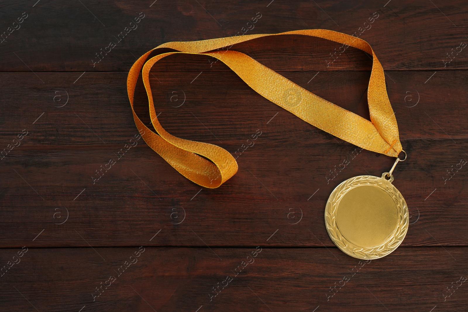 Photo of Gold medal on wooden background, top view. Space for design