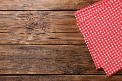 Photo of Red checkered tablecloth on wooden table, top view. Space for text