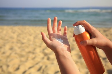 Photo of Child applying sunscreen near sea, closeup. Space for text. Sun protection care