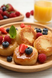 Photo of Delicious cottage cheese pancakes with fresh berries and honey on white wooden table, closeup