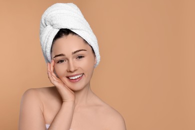 Photo of Portrait of attractive young woman with towel on beige background, space for text. Spa treatment