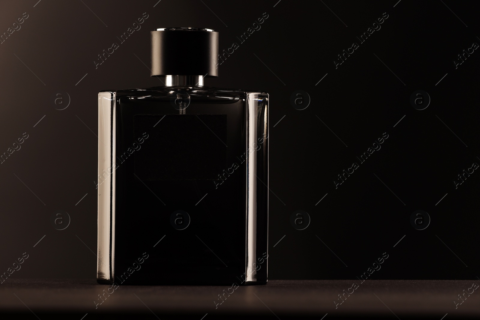 Photo of Luxury men`s perfume in bottle on table against dark background, space for text