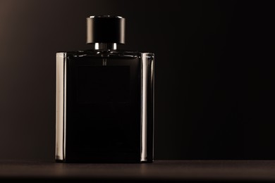 Luxury men`s perfume in bottle on table against dark background, space for text