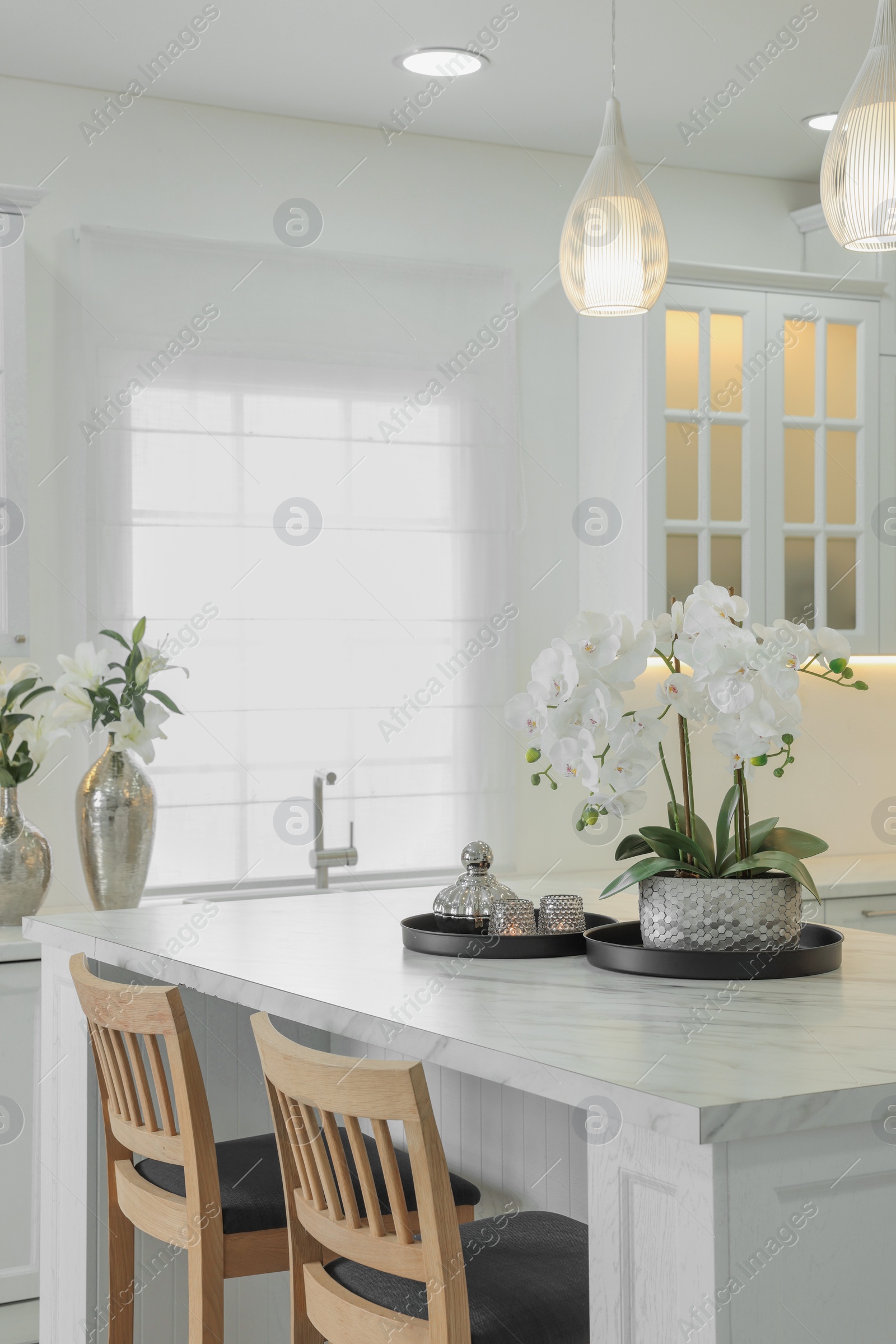 Photo of Beautiful orchid flowers on white marble table in kitchen. Luxury interior