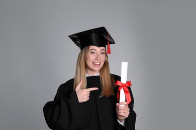 Happy student with diploma on grey background