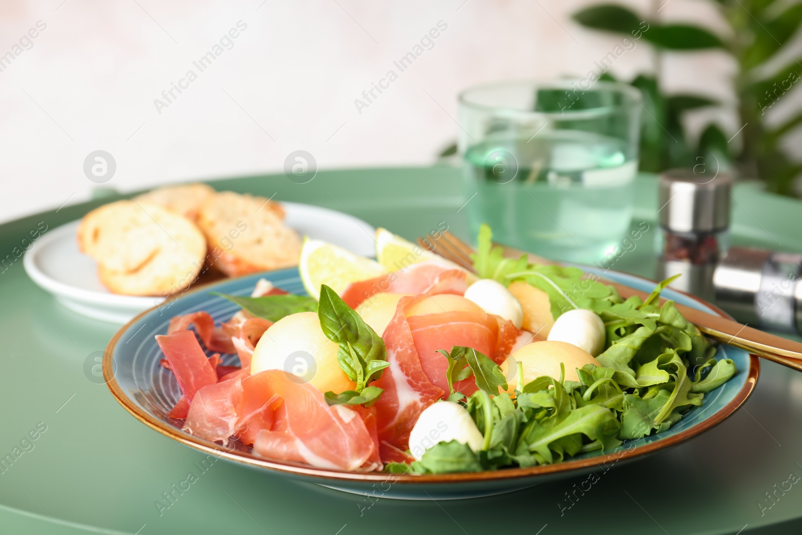 Photo of Plate with melon balls, mozzarella and prosciutto on table