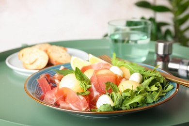 Plate with melon balls, mozzarella and prosciutto on table