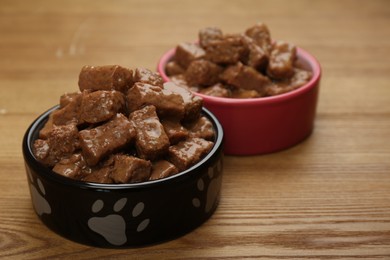 Wet pet food in feeding bowls on wooden background