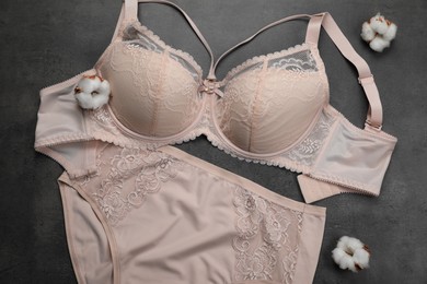 Elegant beige plus size women's underwear and cotton flowers on grey background, flat lay