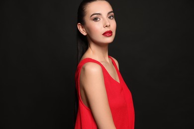 Photo of Portrait of young woman wearing beautiful red lipstick on black background