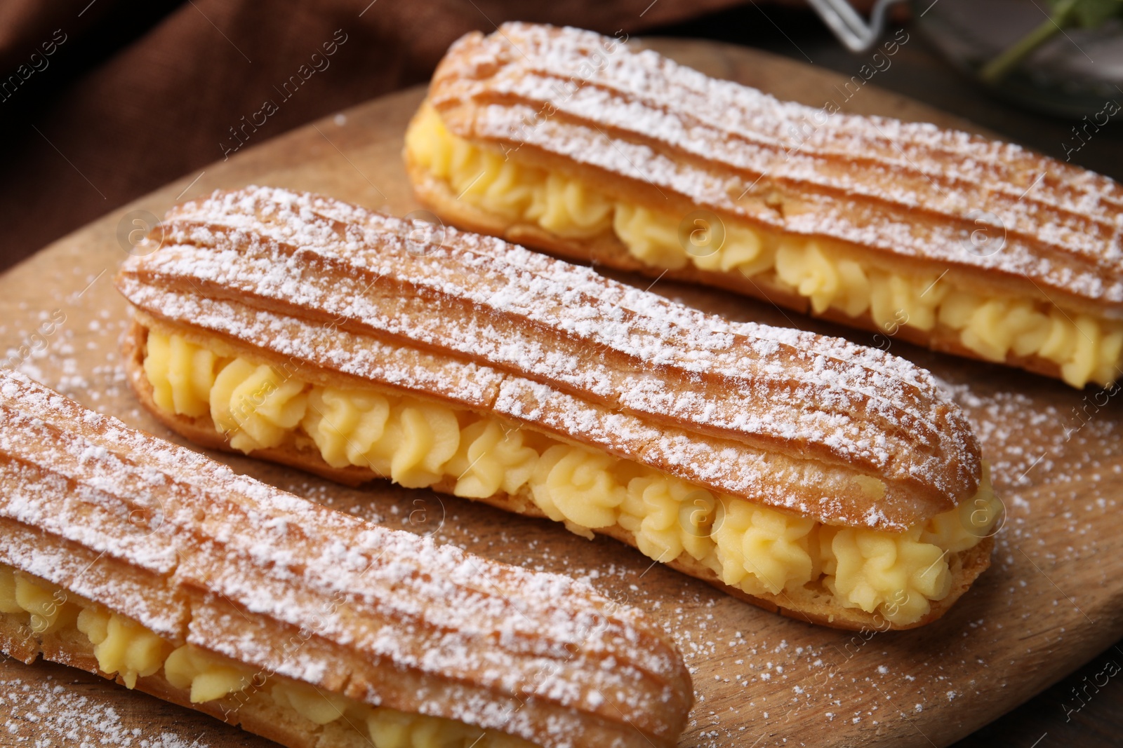 Photo of Delicious eclairs filled with cream on table, closeup