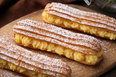 Photo of Delicious eclairs filled with cream on table, closeup