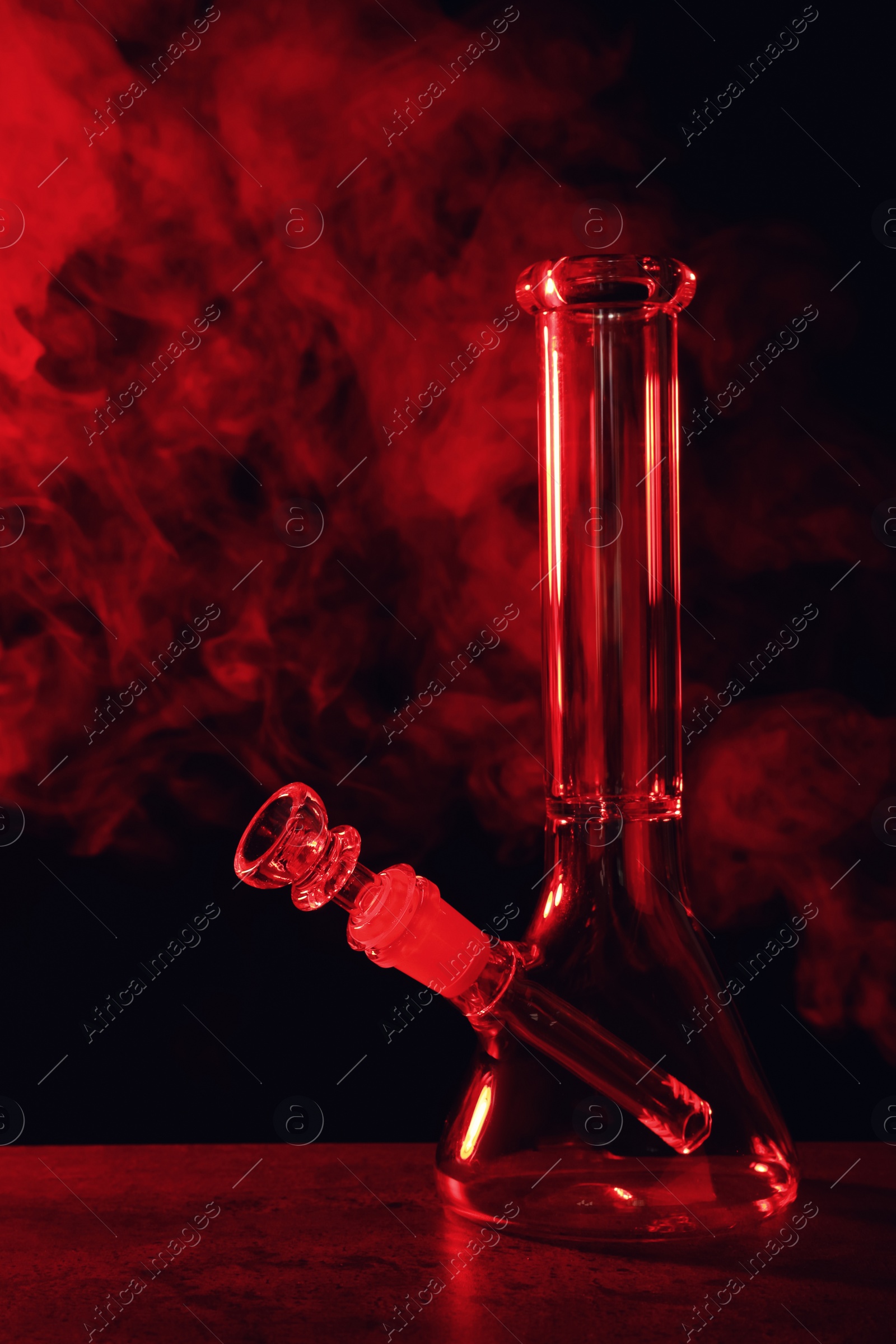 Photo of Glass bong and smoke on black background, toned in red. Smoking device