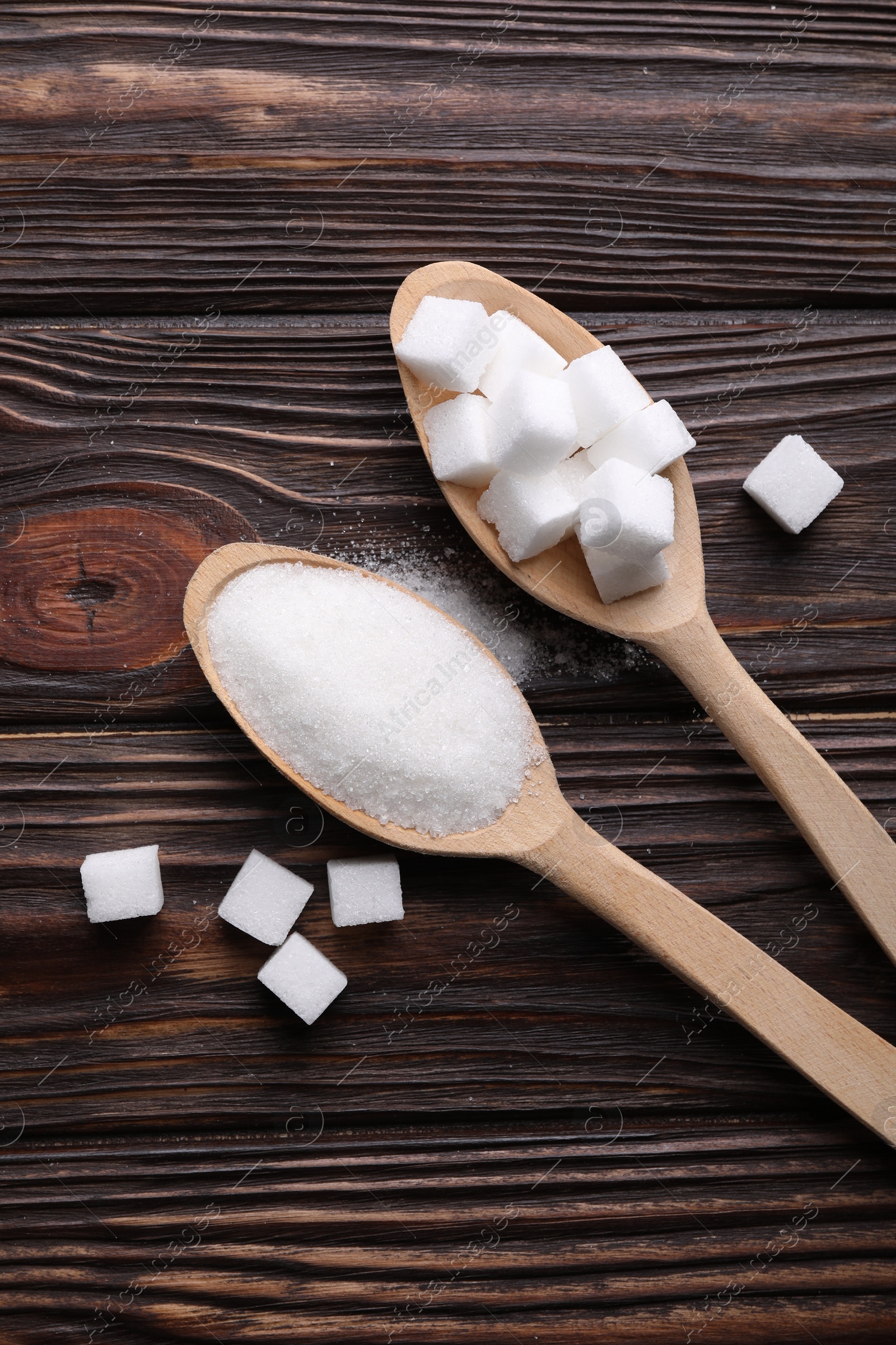 Photo of Spoons with different types of white sugar on wooden table, flat lay