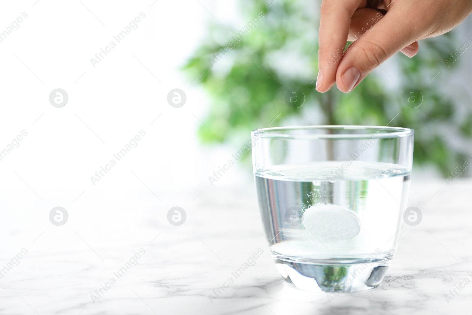 Photo of Woman putting tablet into glass of water indoors, space for text